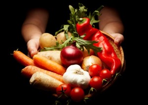female hands holding a basket full of vegetables isolated on black