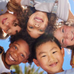 Niños y niñas jugando en círculo al aire libre, celebrando el Día Internacional de la Amistad, en una imagen representativa de los valores de comunidad y solidaridad de Mediolanum Aproxima.